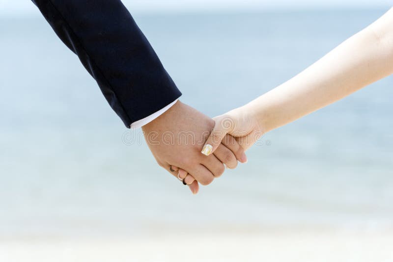 Giovani coppie nell'amore che si tiene per mano insieme mentre camminando sulla spiaggia Concetti dell'amante immagine stock