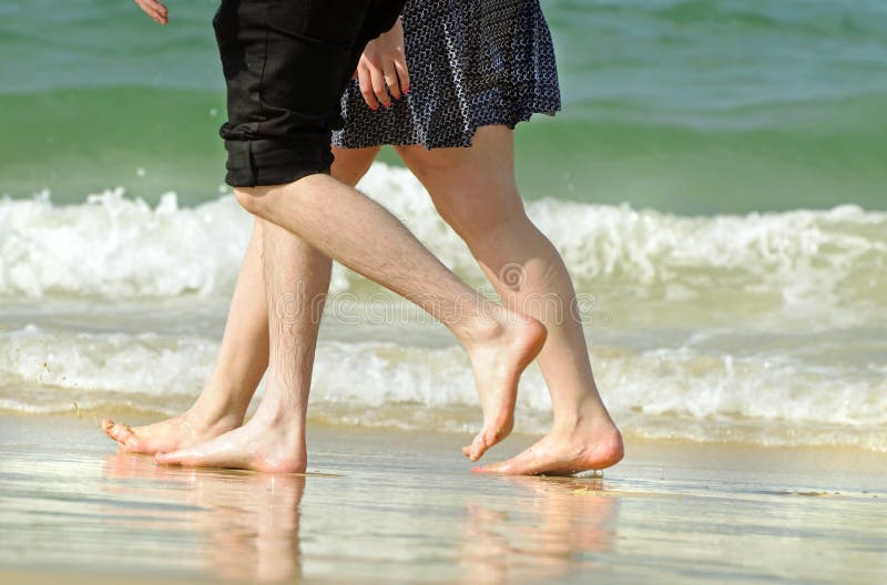 Giovani coppie romantiche in vacanza che cammina lungo la spiaggia fotografie stock Giovani coppie romantiche in vacanza che cammina lungo la spiaggia fotografie stock