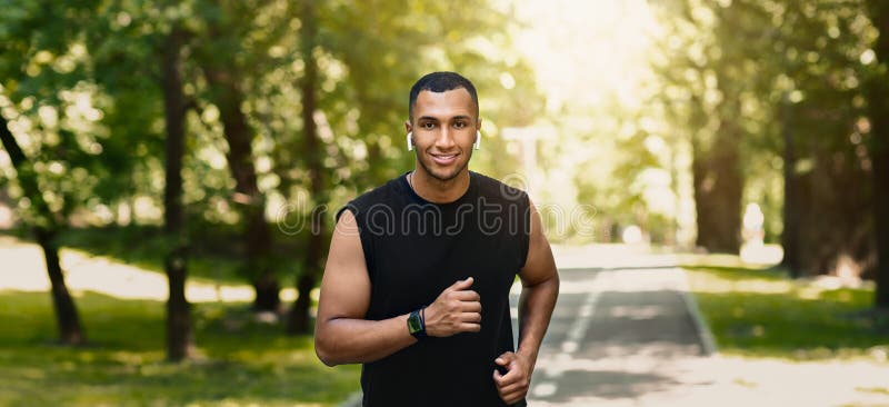 Giovani corridori sorridenti su una pista di jogging nel bel parco verde immagini stock