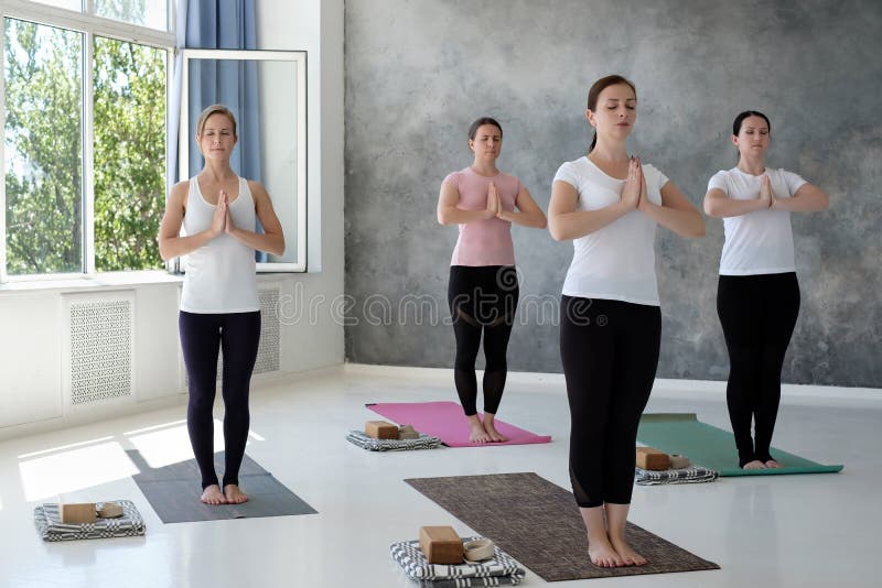 Giovani donne caucasiche che risolvono all'interno stare in Tadasana, posa della montagna fotografie stock libere da diritti Giovani donne caucasiche che risolvono all'interno stare in Tadasana, posa della montagna fotografie stock libere da diritti