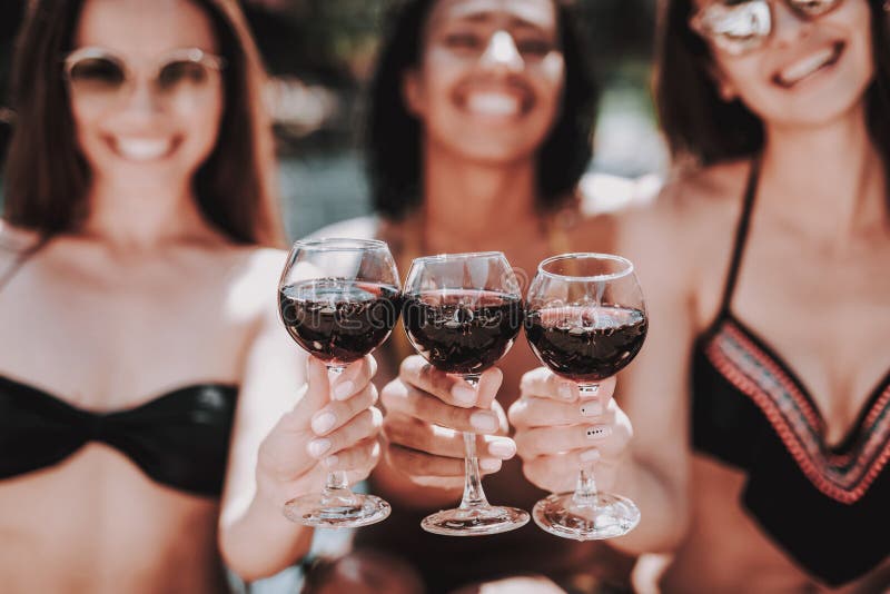 Giovani donne sorridenti che bevono vino al Poolside fotografie stock libere da diritti Giovani donne sorridenti che bevono vino al Poolside fotografie stock libere da diritti