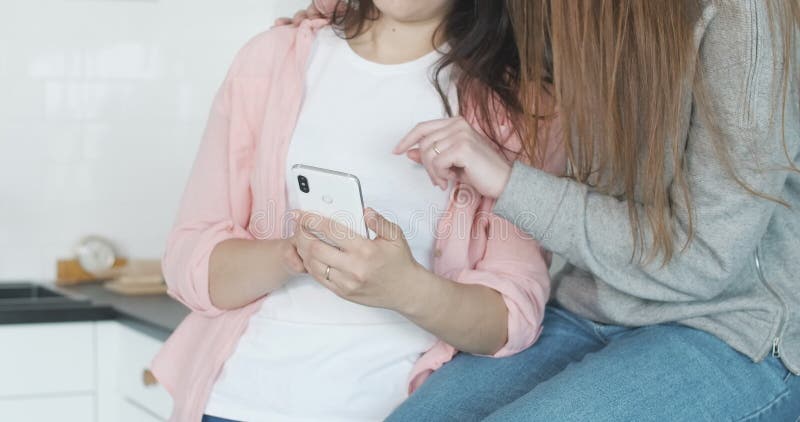 Giovani e inriconoscibili famiglie lesbiche usano smartphone all'interno. ritratto di due donne omosessuali gioiose che parlano e video d archivio