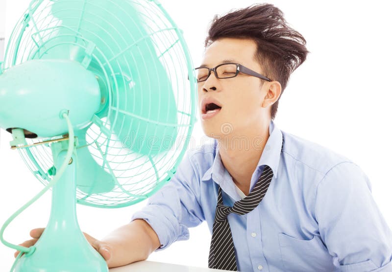 Giovani fan di uso dell'uomo di affari da raffreddarsi fotografie stock libere da diritti Giovani fan di uso dell'uomo di affari da raffreddarsi fotografie stock libere da diritti