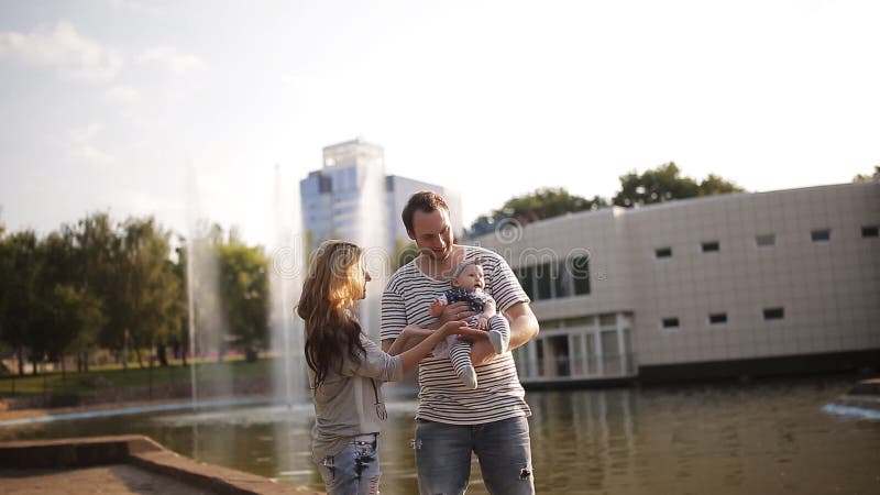 Giovani genitori con una figlia alla fontana al tramonto