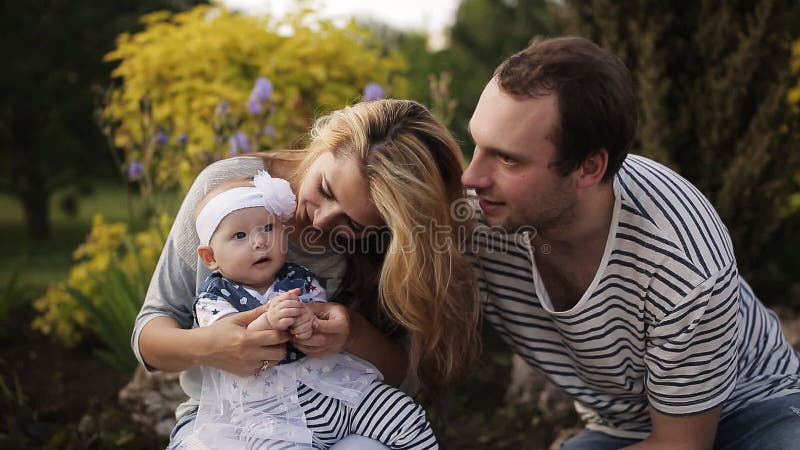 Giovani genitori felici che giocano e che ridono con la sua giovane figlia di estate al tramonto Concetto della famiglia