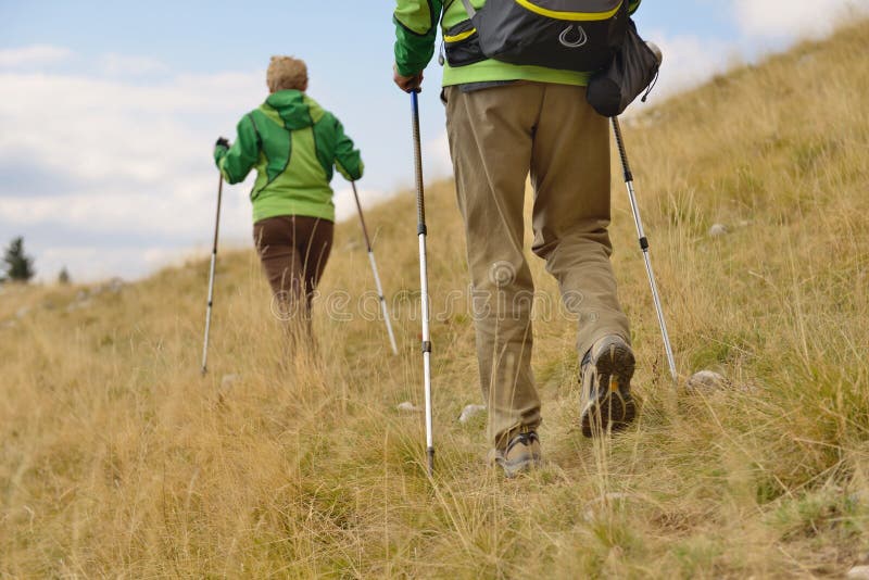Giovani viandanti che camminano con i pali di trekking fotografie stock libere da diritti Giovani viandanti che camminano con i pali di trekking fotografie stock libere da diritti