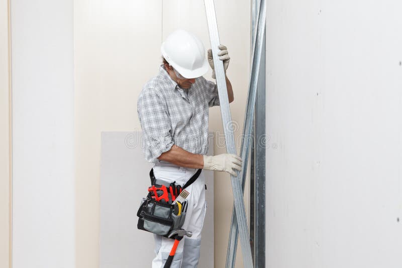 -Gipserholdingtrockenmauer-Metallprofile Mannbauarbeiter- oder in der Nähe von weißen Wand der Fasergipsplatte in der Baustelle. G stockbild