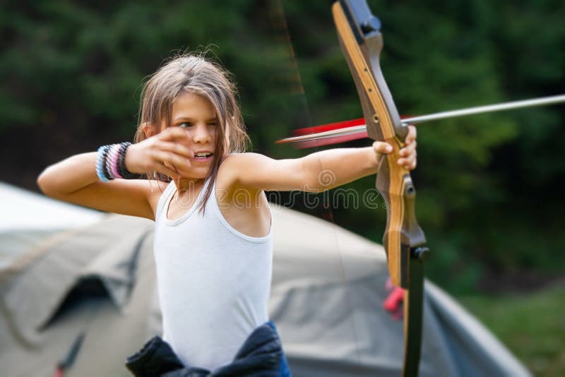 Gipsy girl enjoying with the arrow leaving the bow in a glade camp