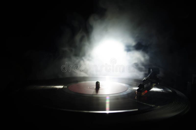 Turntable vinyl record player. Retro audio equipment for disc jockey. Sound technology for DJ to mix & play music. Vinyl record being played against burning fire background with smoke. Turntable vinyl record player. Retro audio equipment for disc jockey. Sound technology for DJ to mix & play music. Vinyl record being played against burning fire background with smoke