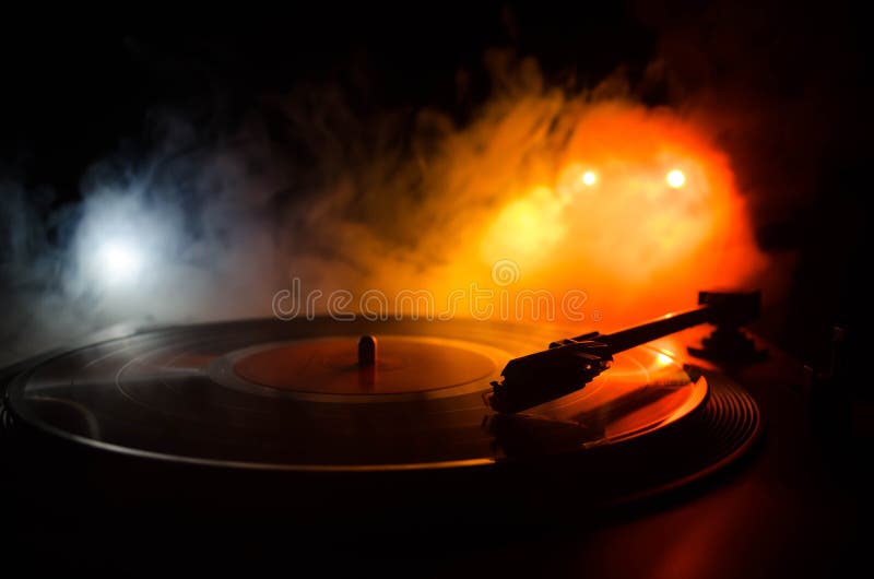 Turntable vinyl record player. Retro audio equipment for disc jockey. Sound technology for DJ to mix & play music. Vinyl record being played against burning fire background with smoke. Turntable vinyl record player. Retro audio equipment for disc jockey. Sound technology for DJ to mix & play music. Vinyl record being played against burning fire background with smoke