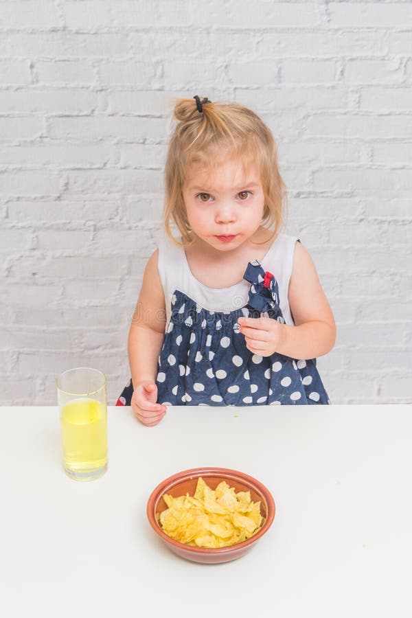 The girl, baby eating potato chips and drinking soda, not health royalty free stock image The girl, baby eating potato chips and drinking soda, not health royalty free stock image