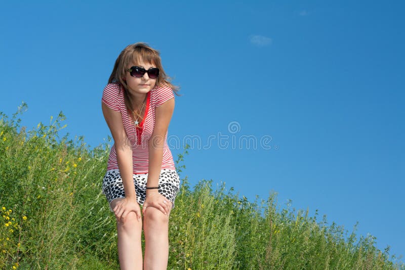 Girl on background of the green herb and sky