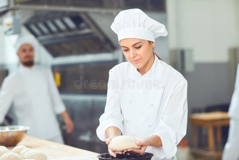 A Girl Baker Smiles with Colleagues at a Bakery. Stock Photo Image of