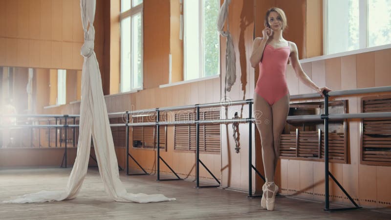 Girl ballerina speaks by phone in a dancing room