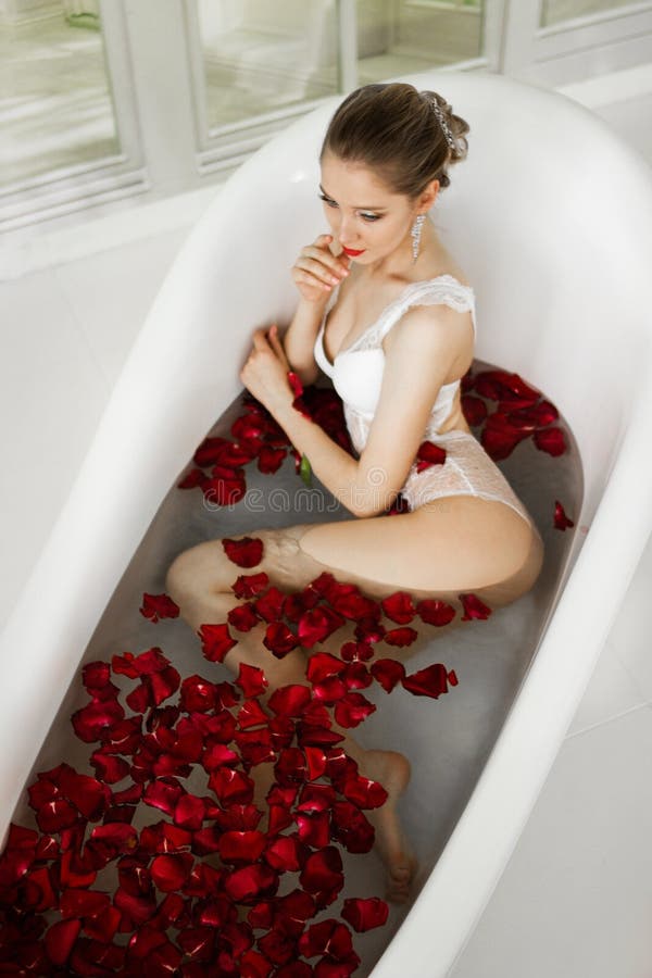 A girl in a bath with rose petals.