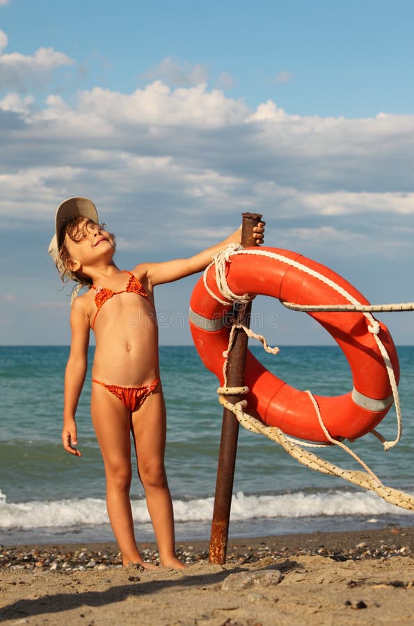 Girl in bathing suit and cap standing on beach