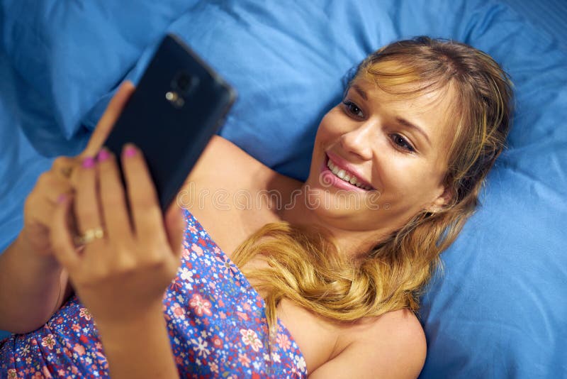 Girl In Bed Reading Love Phone Message From Boyfriend stock photography Girl In Bed Reading Love Phone Message From Boyfriend stock photography
