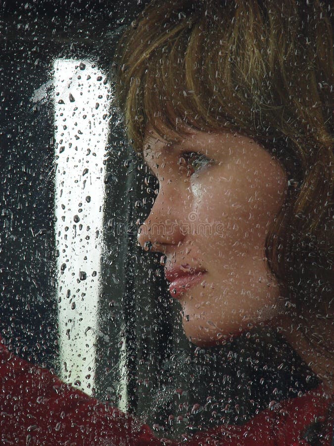 Girl looks thru waterdropped widow glass in rainy weather. Lovely european female stock images, royalty-free photos and pictures