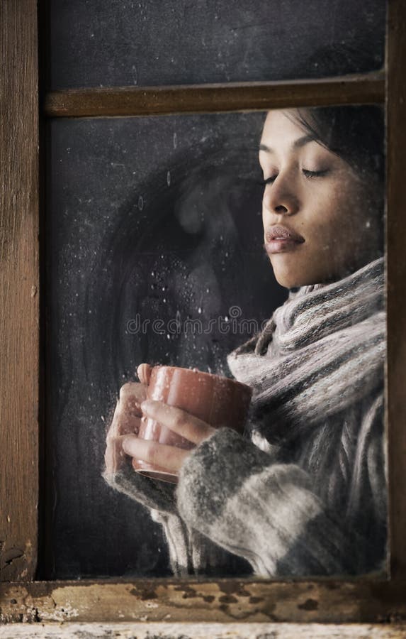 Girl behind window with a cup of coffee or tea