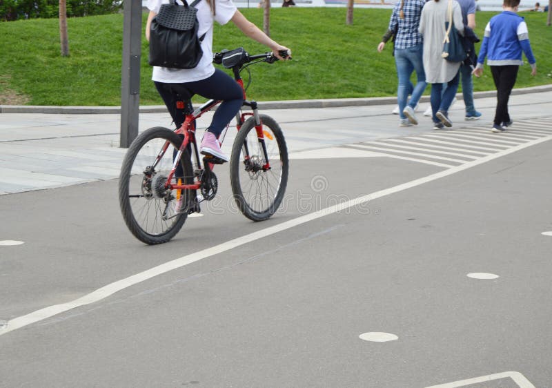 Girl on Bike with Backpack Rides in the Park in the Summer Stock Photo