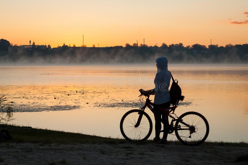 A girl with a bike near the lake in the summer morning royalty free stock photo A girl with a bike near the lake in the summer morning royalty free stock photo