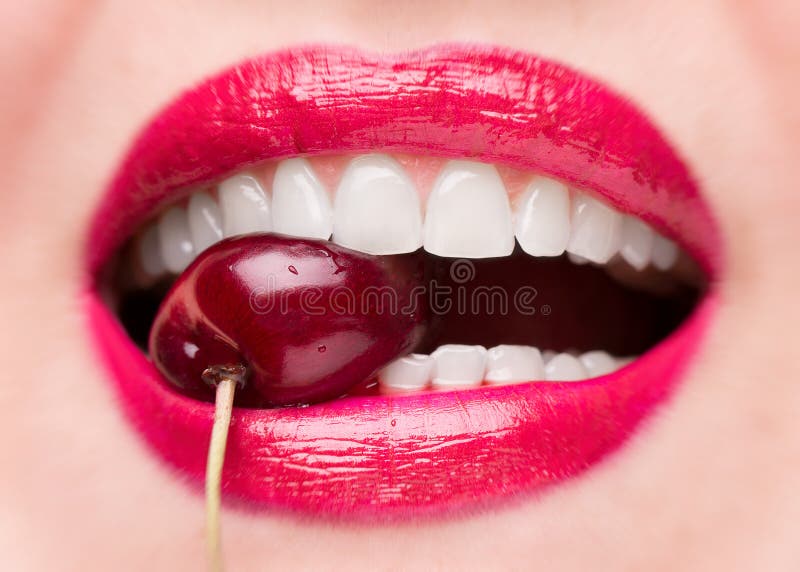 The girl bites a ripe cherry. Cherry in mouth close up