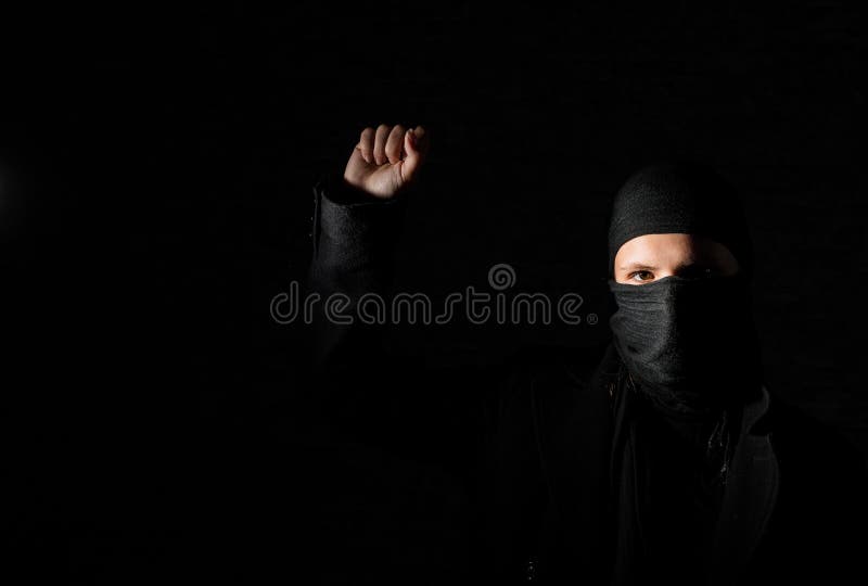Girl In Black Clothes With Hidden Face Protests Raising Fist On Black Background With Copy Space Stock Image Image Of Clothes People
