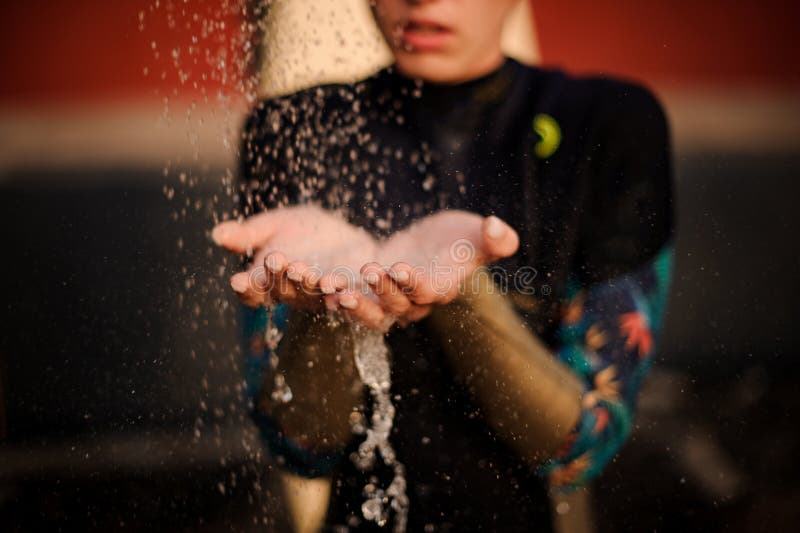 Girl in the black diving suit standing under the shower place hands under water