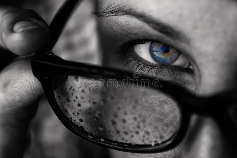 A girl with blue eyes looks over her glasses