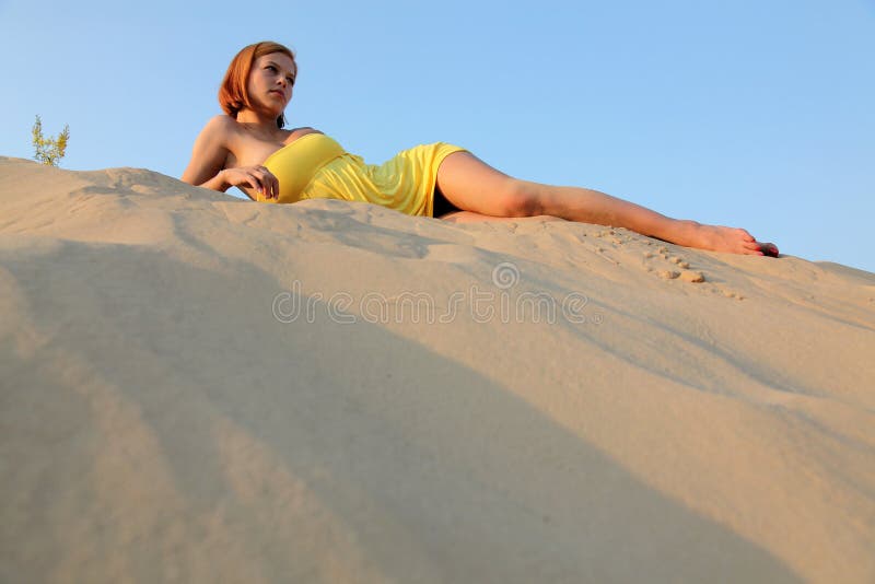 Girl in the blue sky lies on sand stock photography