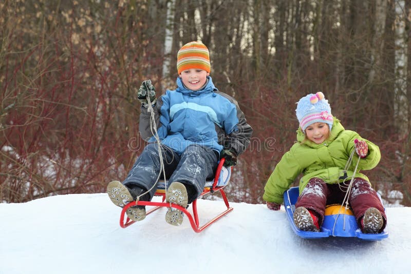 Girl and boy go downward from hill on sledges