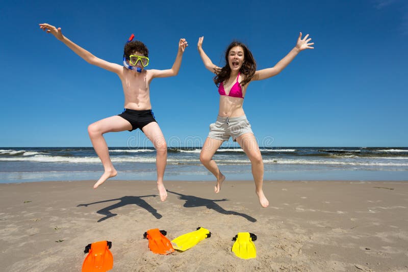 Girl and boy jumping on beach