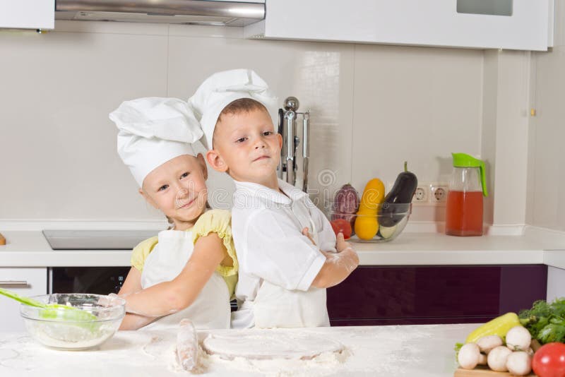 Girl and boy in the kitchen, posing back to back royalty free stock photos Girl and boy in the kitchen, posing back to back royalty free stock photos