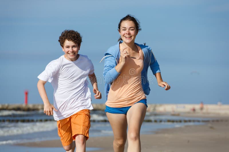 Girl and boy running on beach. 