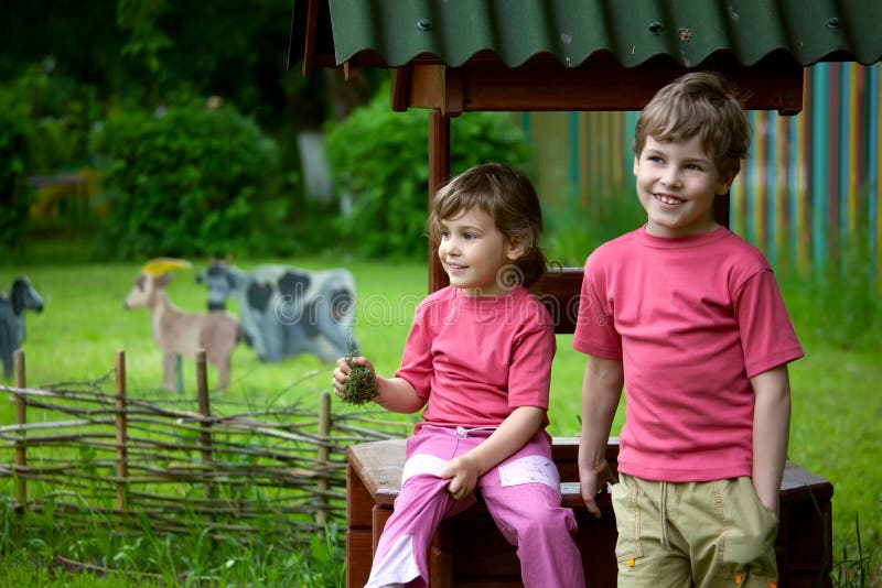 The girl and the boy sit on a well