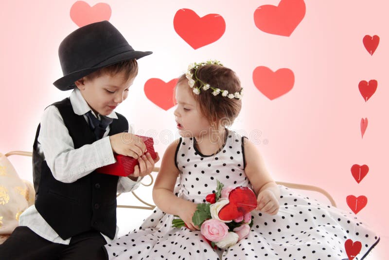 Girl and boy sitting together like lady and gentleman giving present