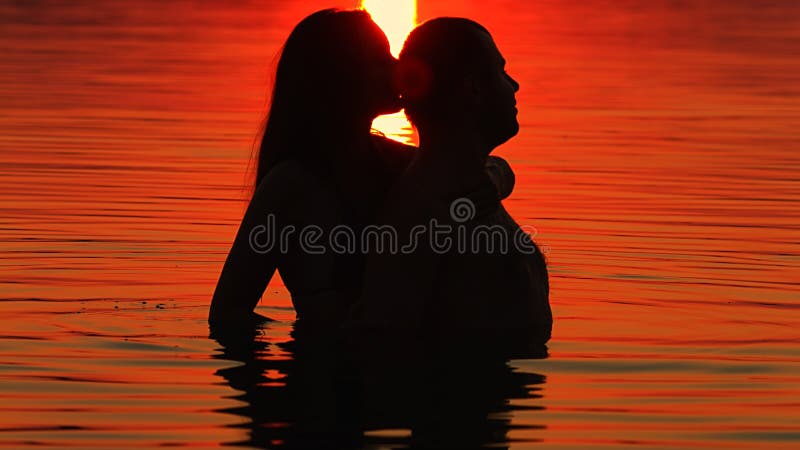 Girl and boy swimming at sunset