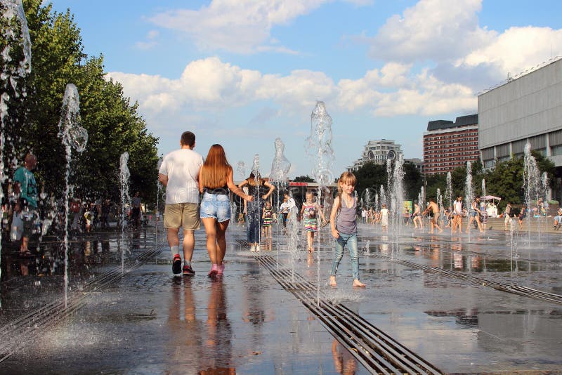 Girl and boy walking along the jets of the water of the Museon fountain.