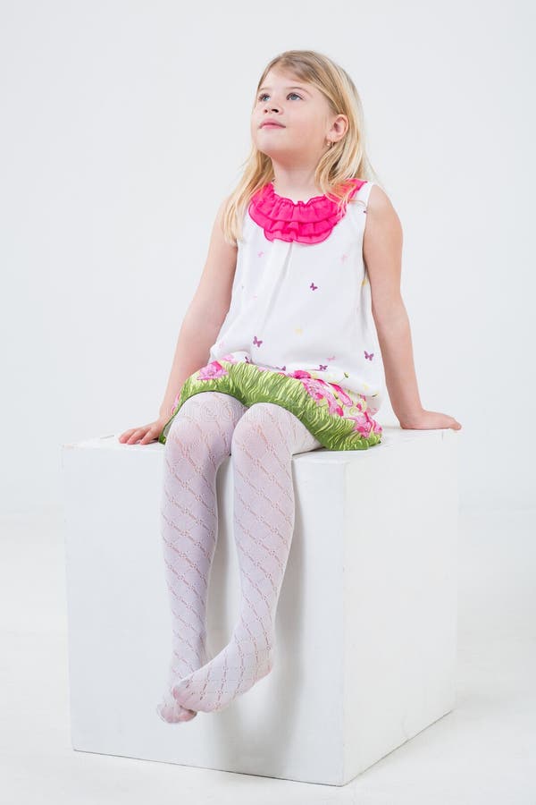 Girl in Bright Dress Sitting on a White Cube Stock Photo - Image of ...
