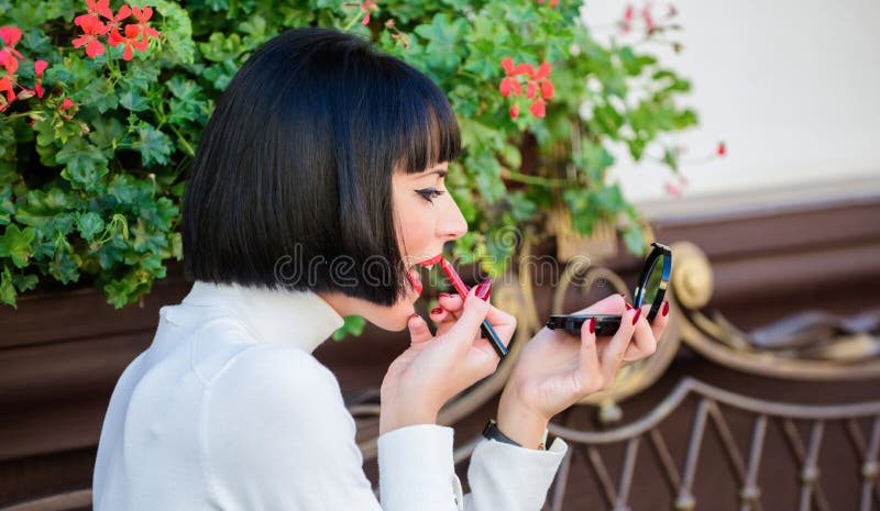Girl brunette with lipstick looking in mirror check her makeup appearance. Girlish secrets concept. Woman making makeup stock photo Girl brunette with lipstick looking in mirror check her makeup appearance. Girlish secrets concept. Woman making makeup stock photo