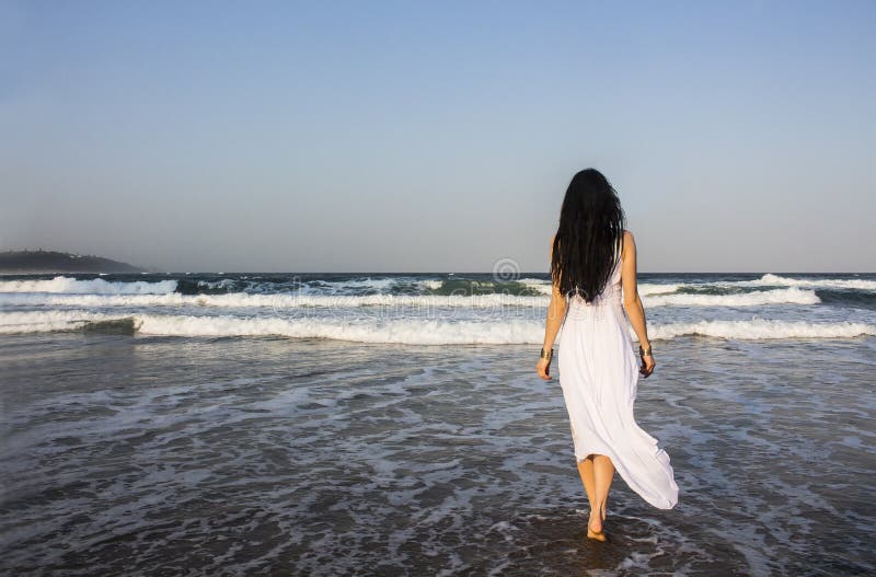 Girl brunette in white dress entering the Indian Ocean.