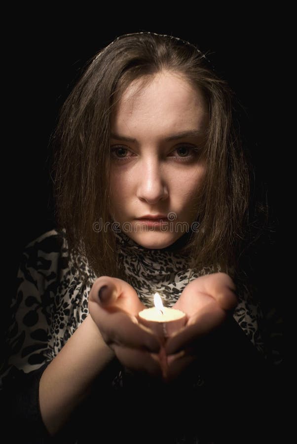 Girl with the candle praying isolated on black background