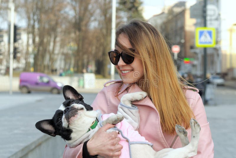 Girl carries a French bulldog as a small child