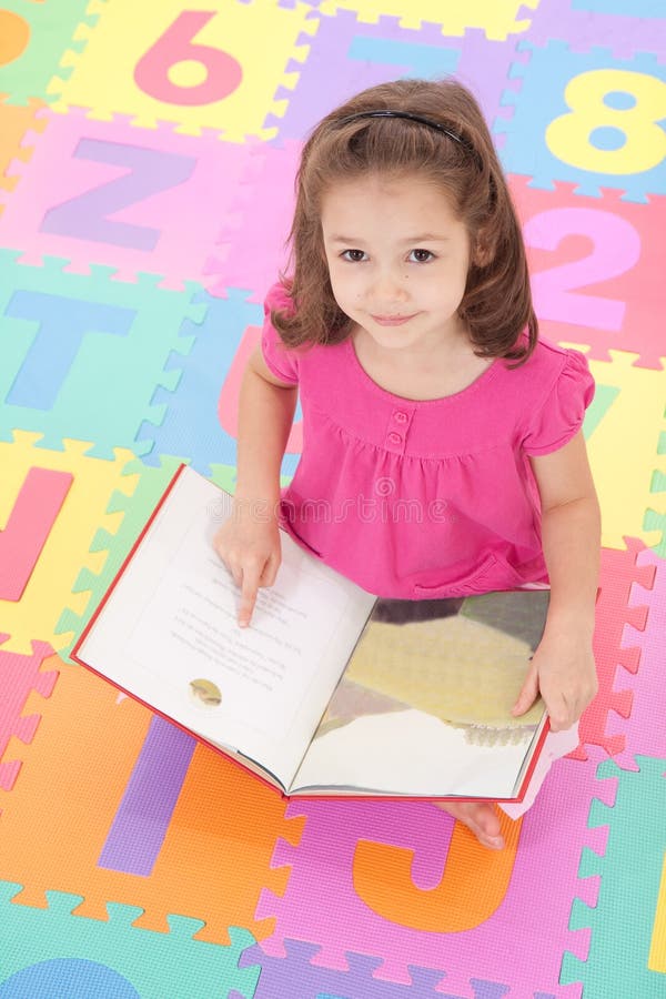 Girl child looking up from reading kids book