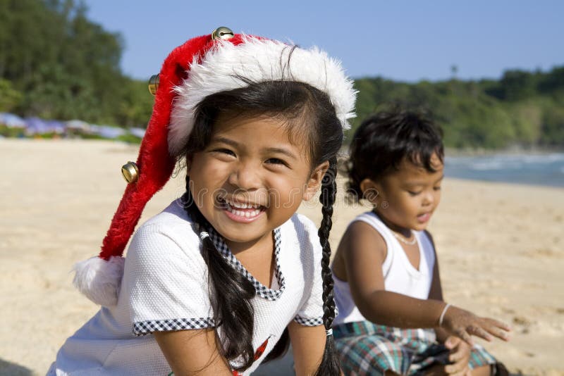 Girl with Christmas hat and boy on beach