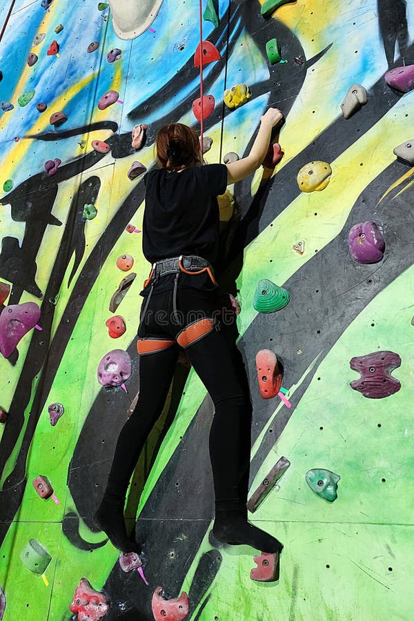 Girl Climbing Up the Wall of the Training Climbing Wall Stock Photo