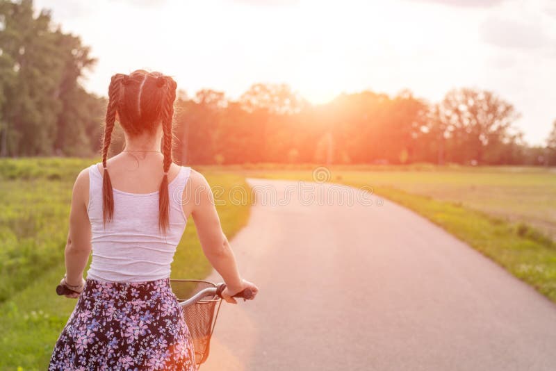 Girl close up with bike at the summer sunset on the road in the city park. Cycling down the street to work at summer sunset royalty free stock images Girl close up with bike at the summer sunset on the road in the city park. Cycling down the street to work at summer sunset royalty free stock images