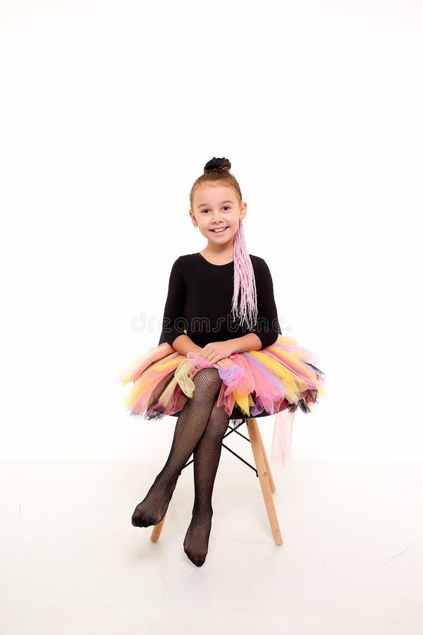 Girl in colorful tutu in the studio with white background during photo shoot. Cute young ballerina inside of the room