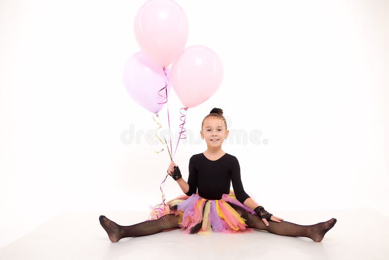 Girl in colorful tutu in the studio with white background during photo shoot with pink balloon. Cute young ballerina