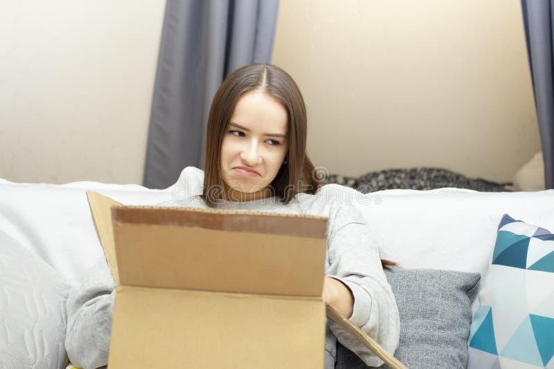 The girl is dissatisfied with the received parcel, makes a grimace when opening the box, the product was broken, damaged, broken.